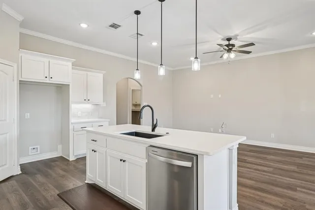 a kitchen with a sink dishwasher and white cabinets with wooden floor