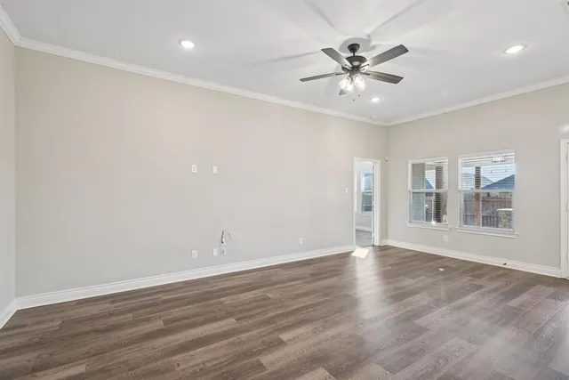 an empty room with wooden floor and ceiling fan