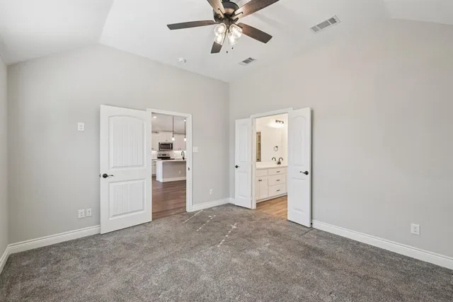 an empty room with chandelier fan and windows