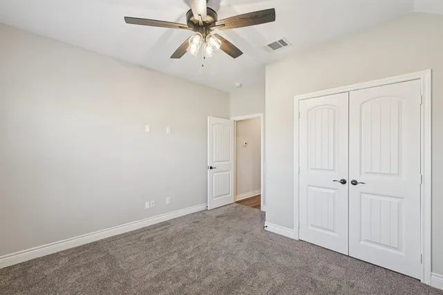 an empty room with closet and a chandelier fan