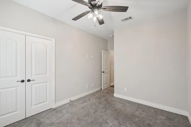 an empty room with a ceiling fan and a window