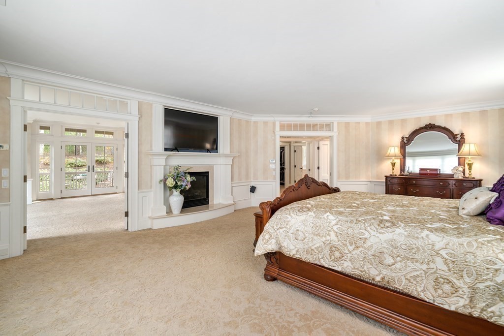 145 Dutton Road Sudbury, MA 01776 - Photo 22 of 41 a bed sitting in a spacious bedroom next to a window with a flat screen tv and a fireplace