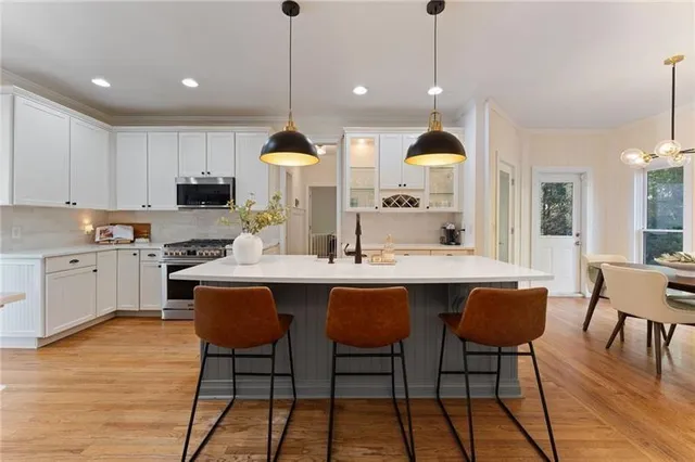 a kitchen with stainless steel appliances kitchen island granite countertop a sink a stove a dining table and chairs