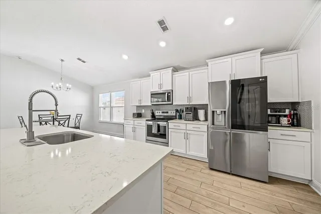 a kitchen with kitchen island granite countertop a stove a sink a refrigerator and a stove with wooden floor