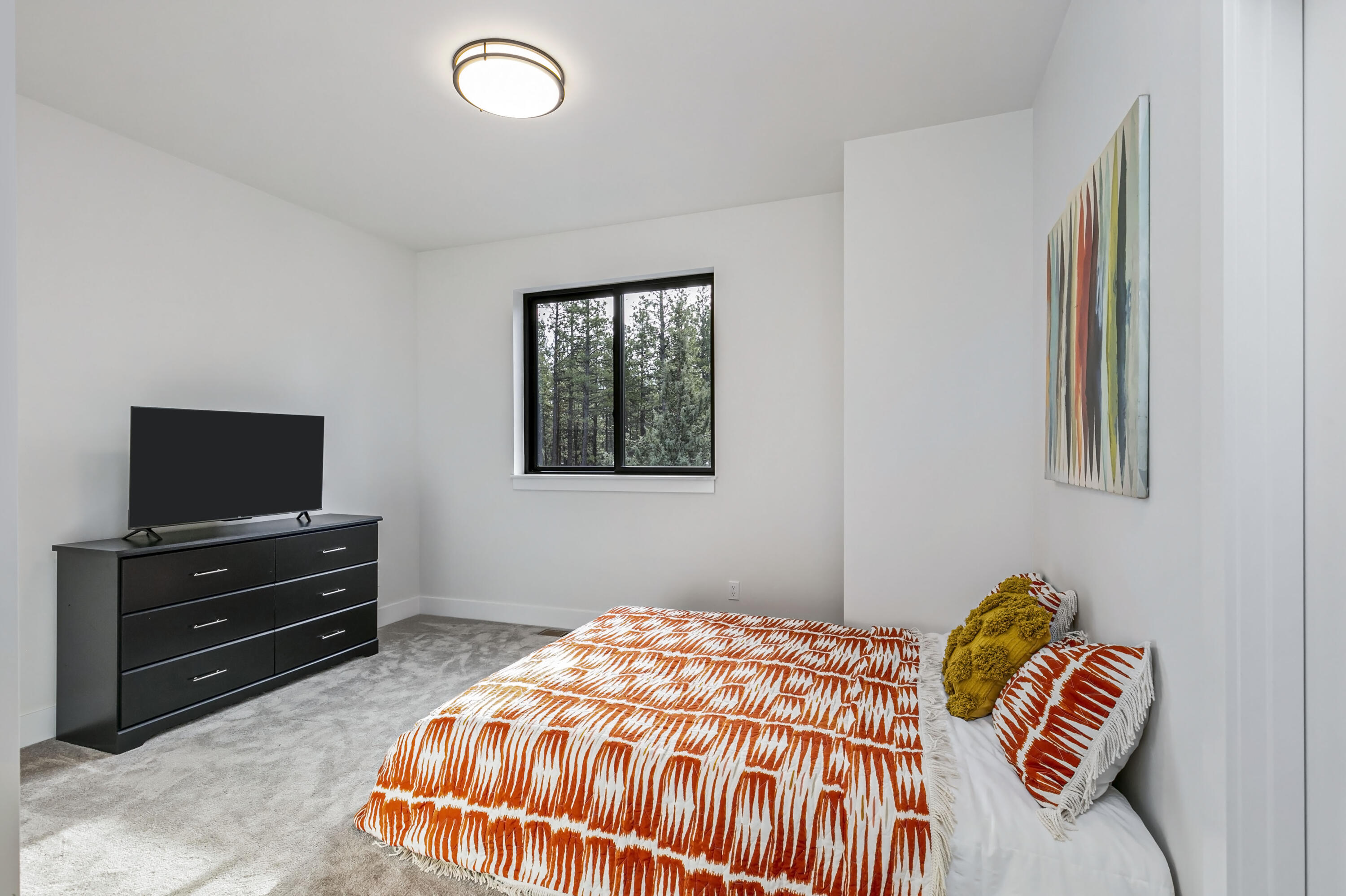 19550 Buck Canyon Road Bend, OR 97702 - Photo 18 of 28 a bedroom with a bed and a flat screen tv