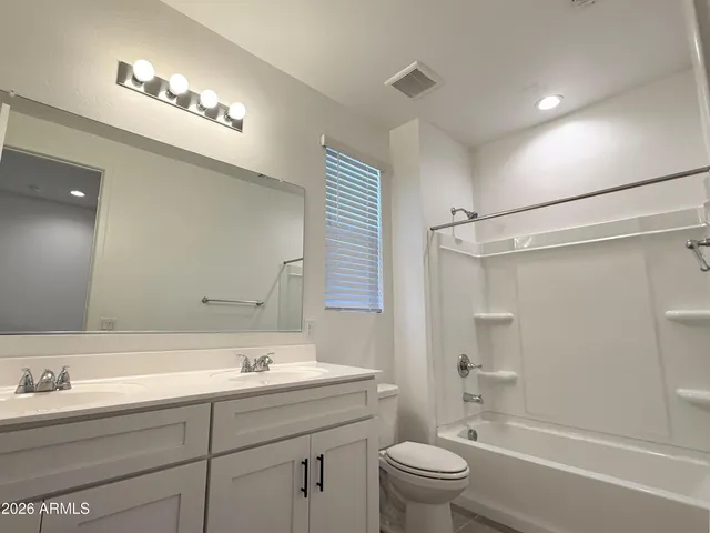 a bathroom with a toilet a sink a mirror a bathtub and vanity