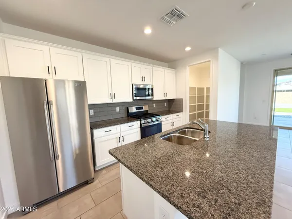 a kitchen with stainless steel appliances granite countertop a refrigerator a stove a sink and a microwave