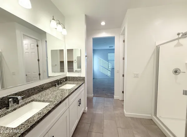 a bathroom with a granite countertop double vanity sink and mirror