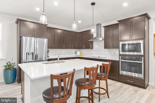 a kitchen with stainless steel appliances granite countertop a kitchen island a table and chairs in it