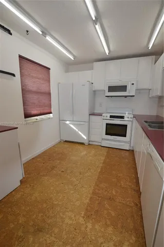 a large white kitchen with stainless steel appliances granite countertop a stove a sink and a microwave