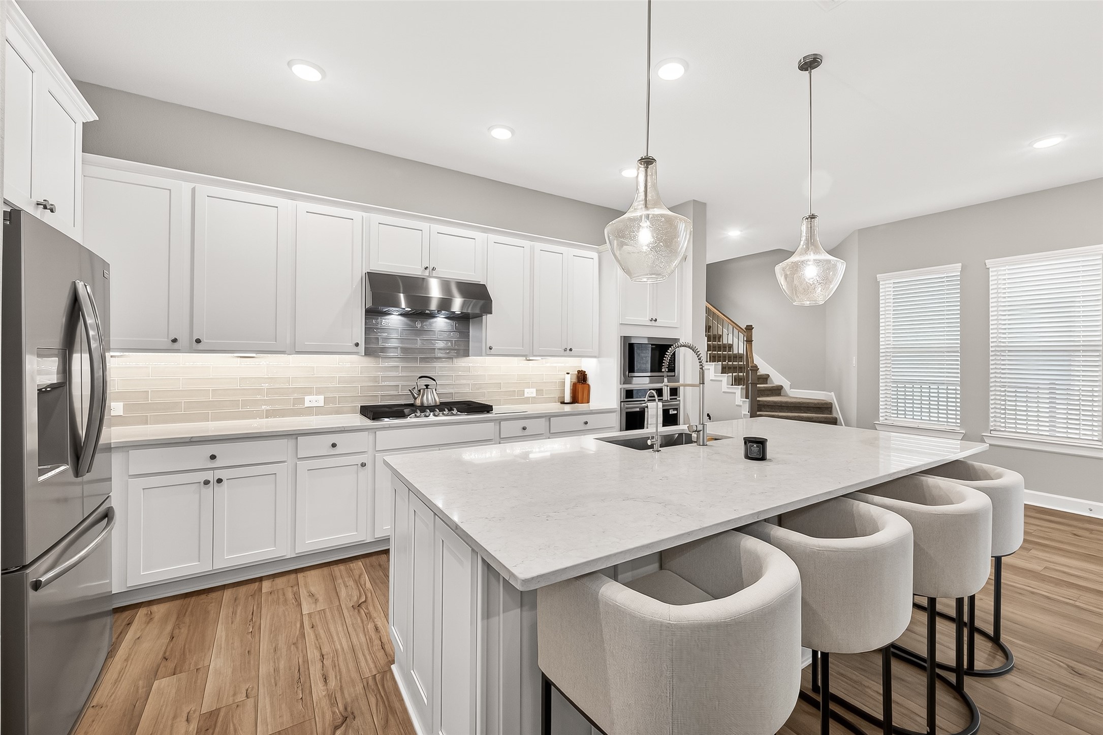 11226 Common Hackberry Street Cypress, TX 77433 - Photo 5 of 17 a kitchen with a white center island a sink cabinets and stainless steel appliances