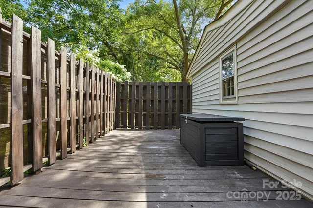 a view of backyard with wooden fence and large trees
