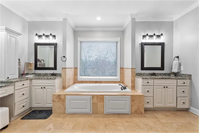 a bathroom with a granite countertop sink double vanity mirror and a bathtub