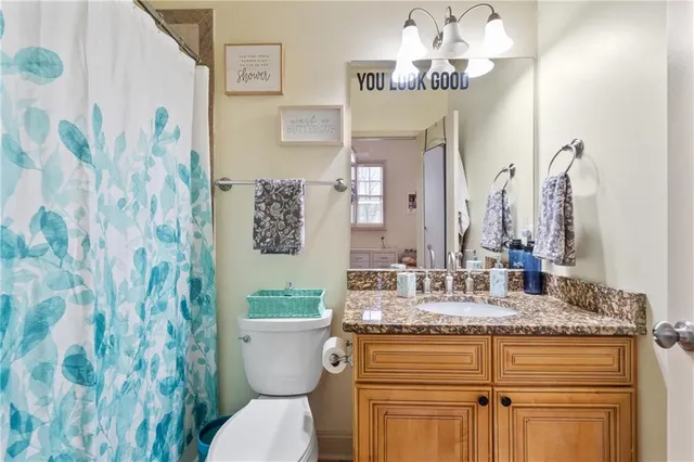a bathroom with a granite countertop toilet sink and mirror