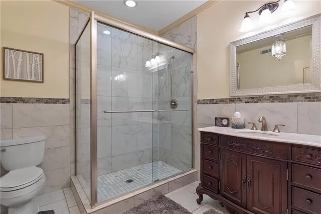 a bathroom with a toilet a sink a glass door a shower a mirror and vanity