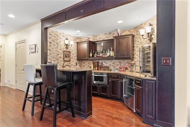 a kitchen with stainless steel appliances kitchen island granite countertop a table chairs sink and cabinets