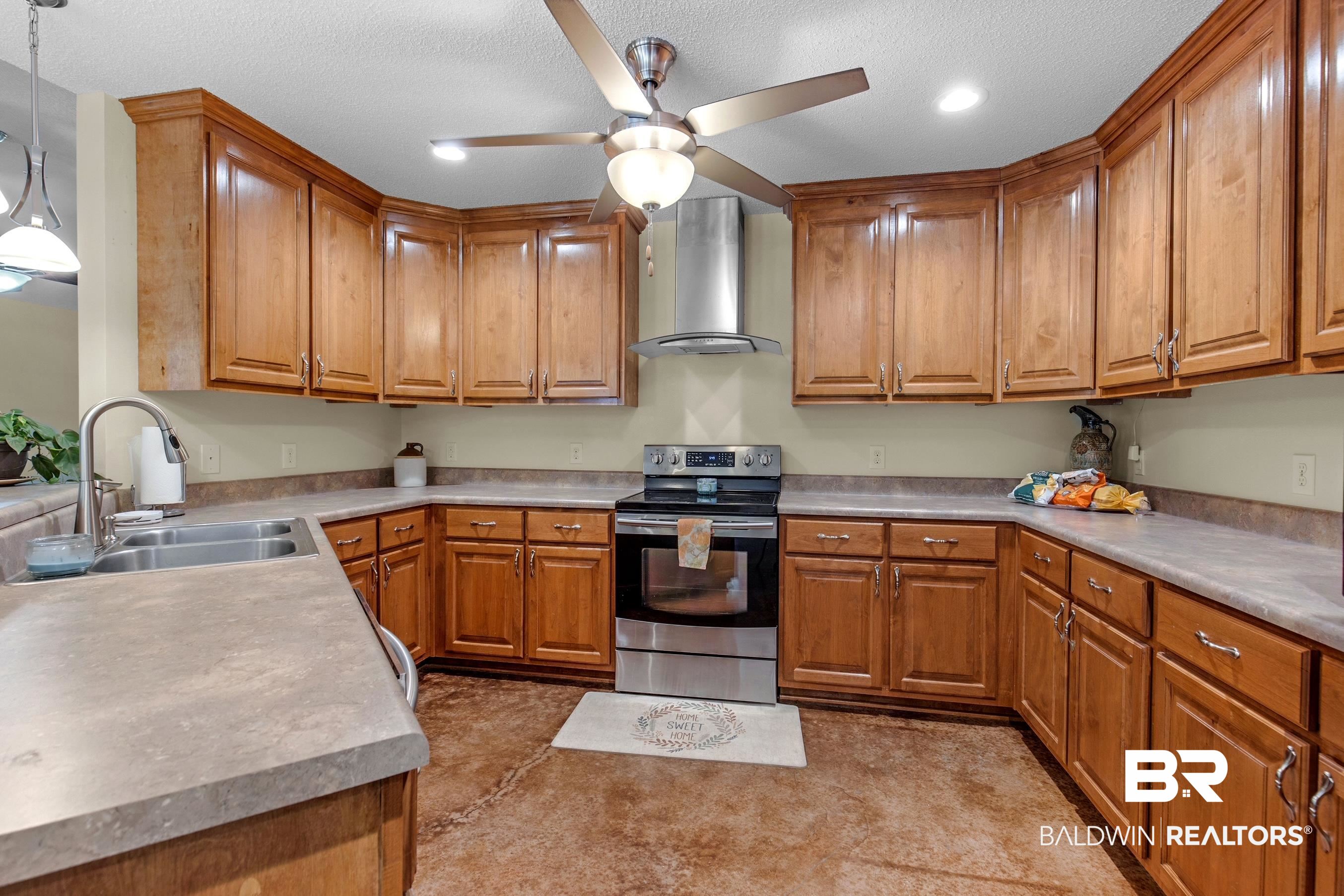 36087 Byrd Road Stapleton, AL 36578 - Photo 18 of 27 Kitchen featuring decorative light fixtures, electric range, sink, wall chimney range hood, and ceiling fan