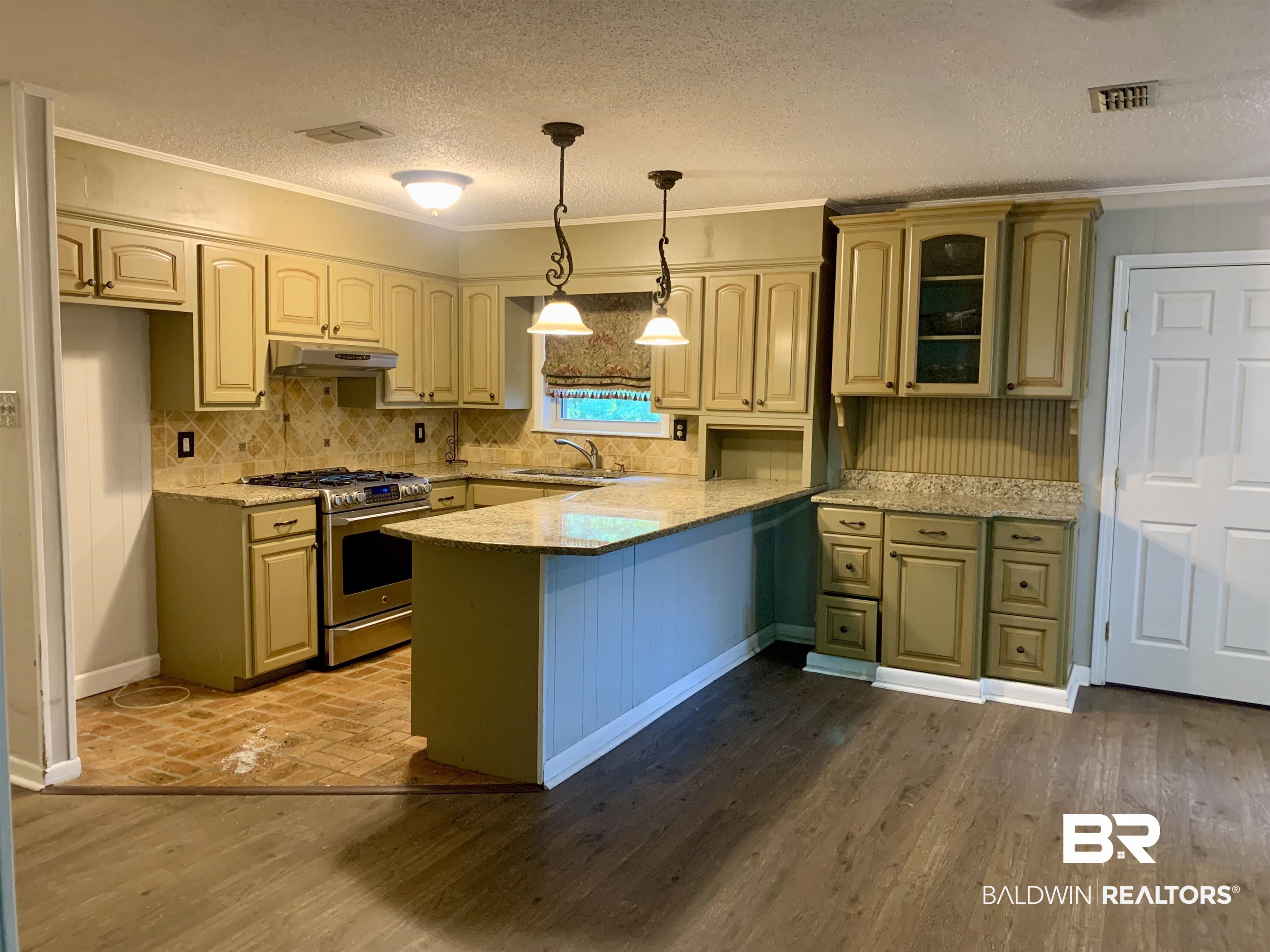 2708 E Road Mobile, AL 36693 - Photo 3 of 12 Kitchen featuring hanging light fixtures, high end stove, a textured ceiling, kitchen peninsula, and backsplash