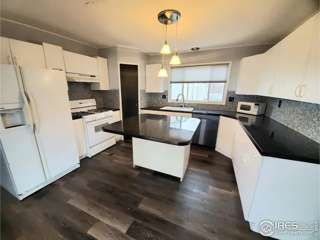 a kitchen with stainless steel appliances a refrigerator a stove a sink dishwasher and white cabinets with wooden floor