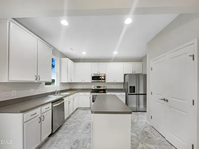 a kitchen with a sink a stove a refrigerator and white cabinets