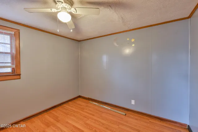 en empty room with wooden floor and fan