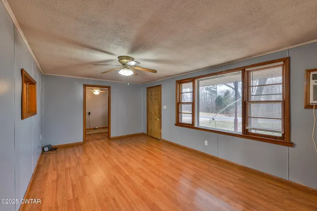 a view of an empty room with a window and wooden floor
