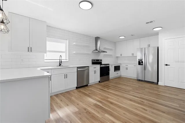 a kitchen with stainless steel appliances sink a refrigerator and white cabinets