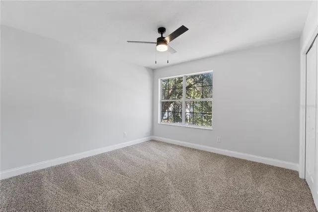 an empty room with ceiling fan and windows