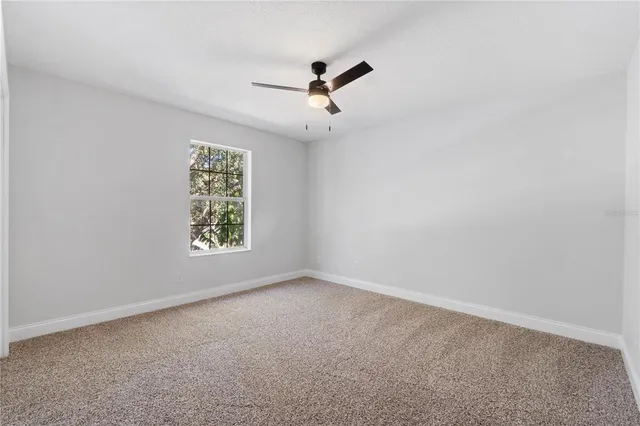 an empty room with windows and ceiling fan view
