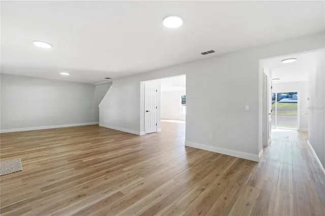 an empty room with wooden floor and windows