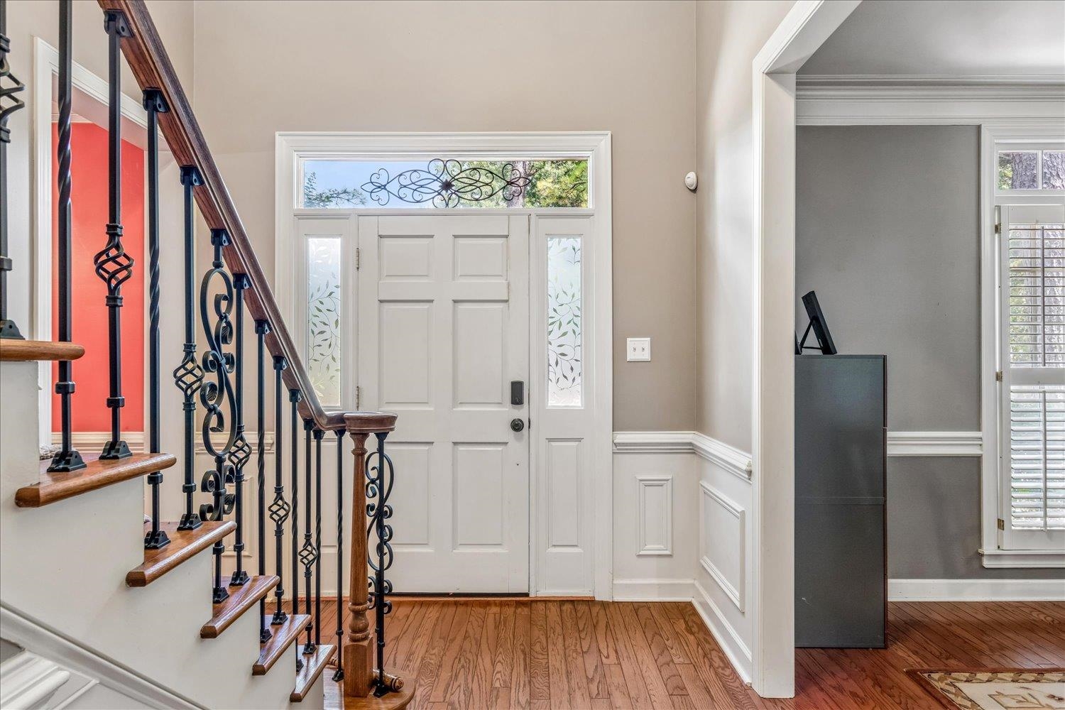 65 Summer Grove Road Memphis, TN 38018 - Photo 7 of 38 Hardwood flooring throughout, decorative iron and wood-finish staircase, wainscoting details, paneled front door with decorative glass sidelights, and transom window