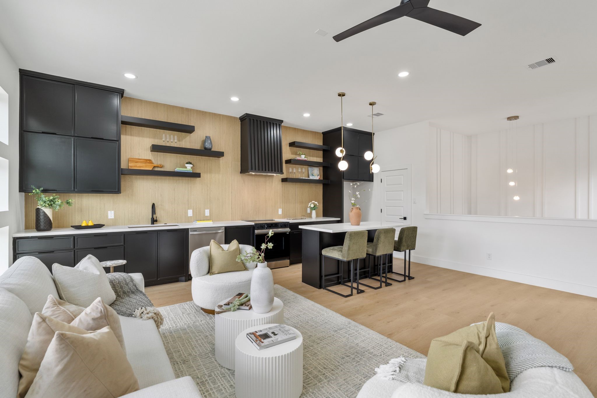 7321 Laura Koppe Road Houston, TX 77028 - Photo 6 of 41 Sleek open-concept living area with a modern kitchen featuring black cabinetry, open shelving, and a spacious island with seating. Cozy lounge space offers comfort and style, perfect for entertaining.