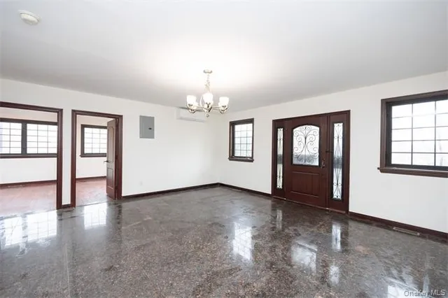an empty room with wooden floor chandelier and windows
