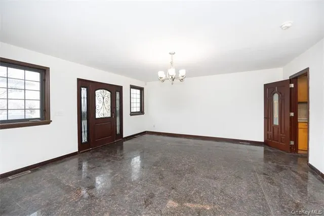 a view of an empty room with window and chandelier