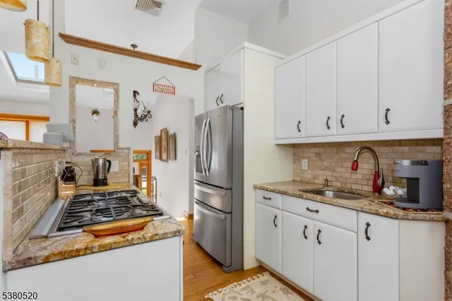 a kitchen with stainless steel appliances granite countertop a refrigerator stove and white cabinets