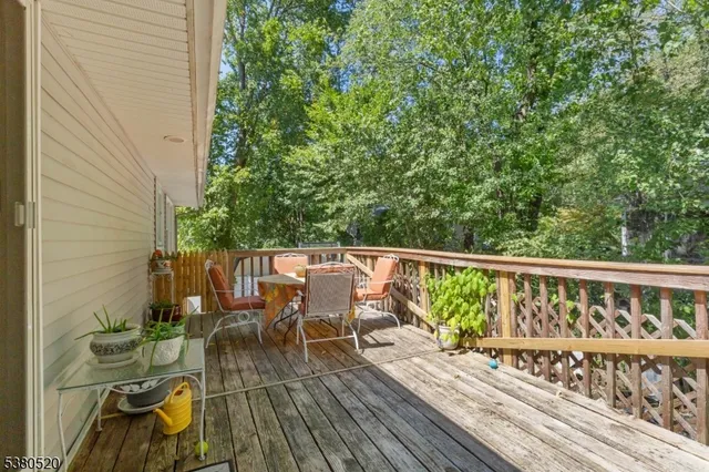 a balcony with wooden floor outdoor seating and yard in the back