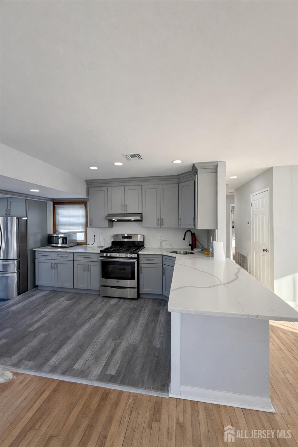 30 Falmouth Road Iselin, NJ 08830 - Photo 9 of 23 a large kitchen with kitchen island a stove a sink dishwasher and a refrigerator with wooden floor