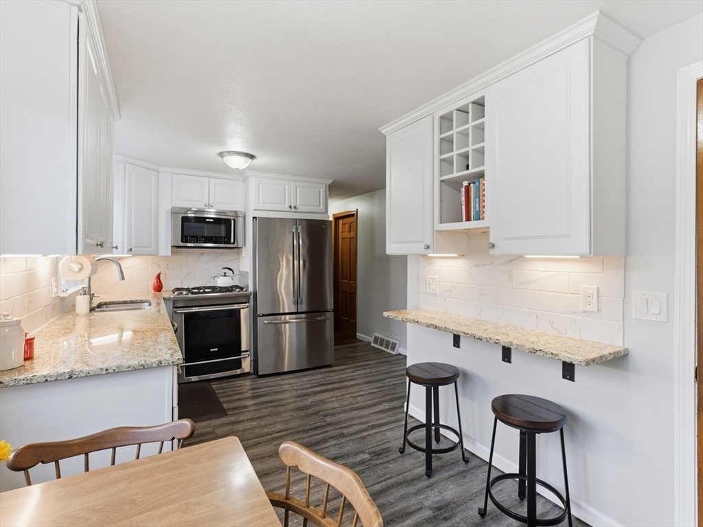 97 Robak Drive Chicopee, MA 01020 - Photo 4 of 41 a kitchen with stainless steel appliances a stove a refrigerator island cabinets and chairs