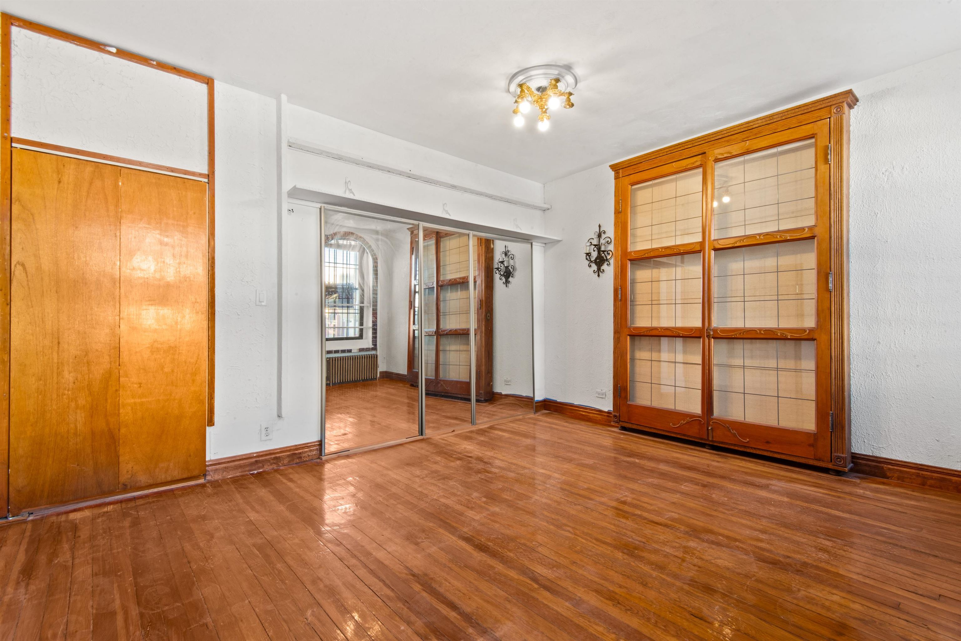 an empty room with wooden floor and windows with curtains