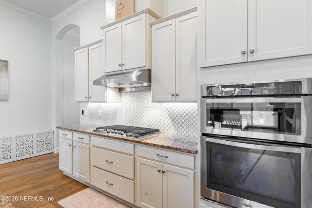 a kitchen with stainless steel appliances granite countertop a sink a stove a refrigerator and chairs