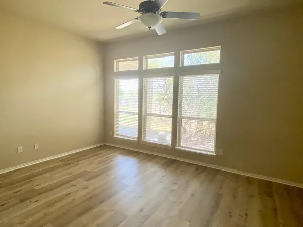 an empty room with wooden floor and windows