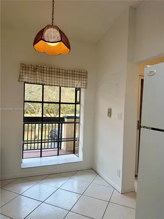 a view of an empty room with window and chandelier