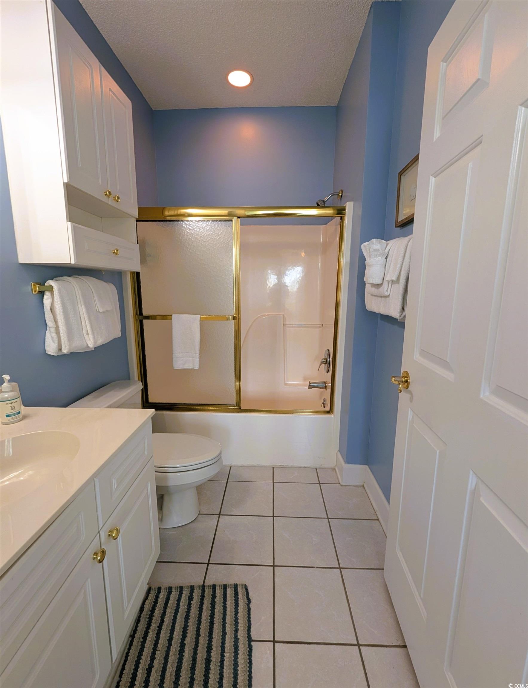 1512 Lanterns Rest Road, Unit 201 Myrtle Beach, SC 29579 - Photo 13 of 23 Bathroom with light tile patterned flooring, vanity, shower / bath combination with glass door, and a textured ceiling