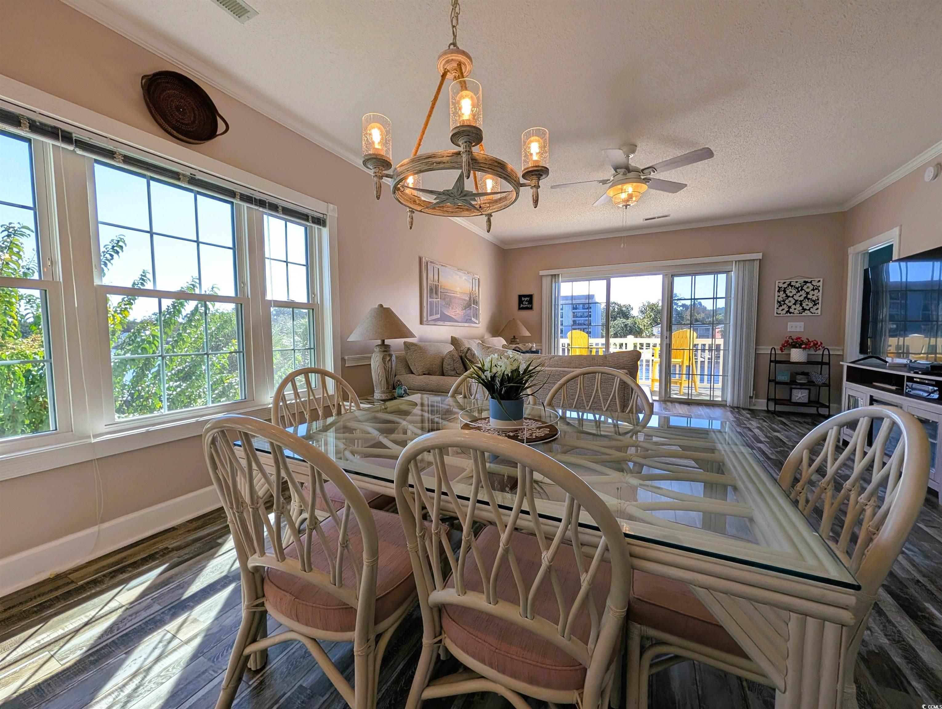 1512 Lanterns Rest Road, Unit 201 Myrtle Beach, SC 29579 - Photo 5 of 23 Dining area with ornamental molding, a chandelier, dark wood-type flooring, a ceiling fan, and a textured ceiling