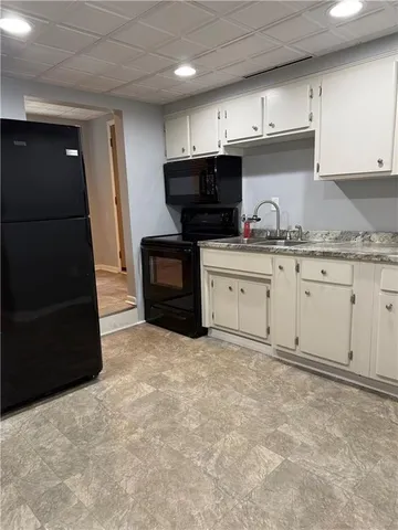 a kitchen with granite countertop a refrigerator and a stove top oven