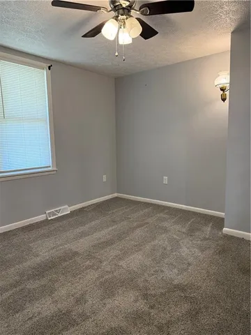 an empty room with a chandelier fan and windows