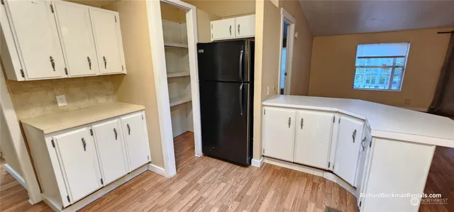 a kitchen with white cabinets and refrigerator