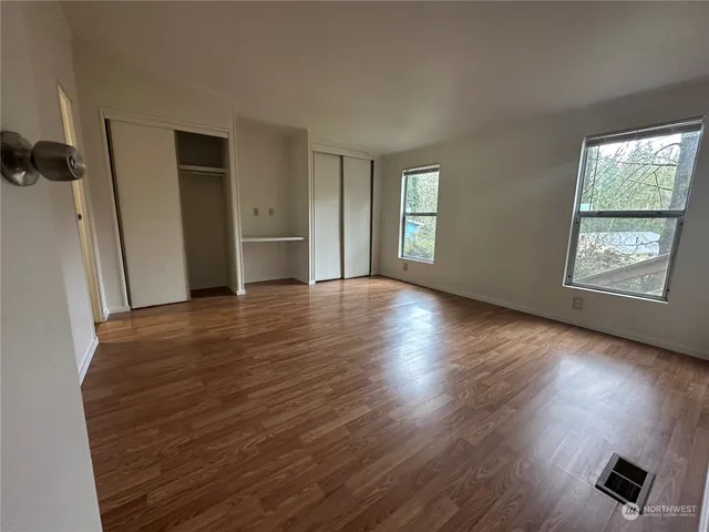 an empty room with wooden floor and windows