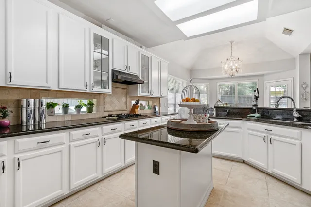 a kitchen with white cabinets and sink
