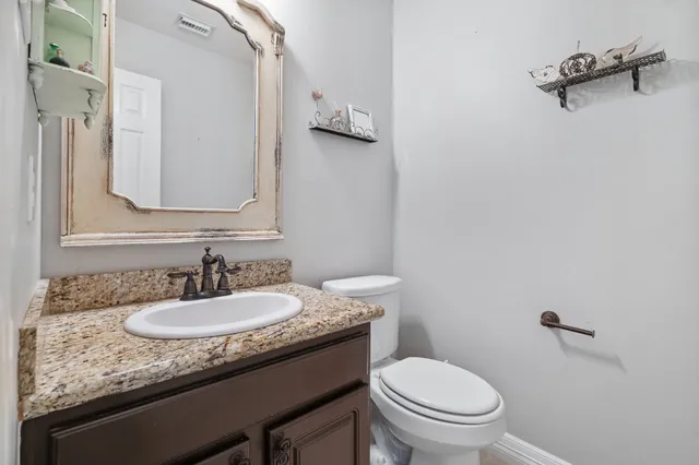 a bathroom with a granite countertop sink toilet and mirror